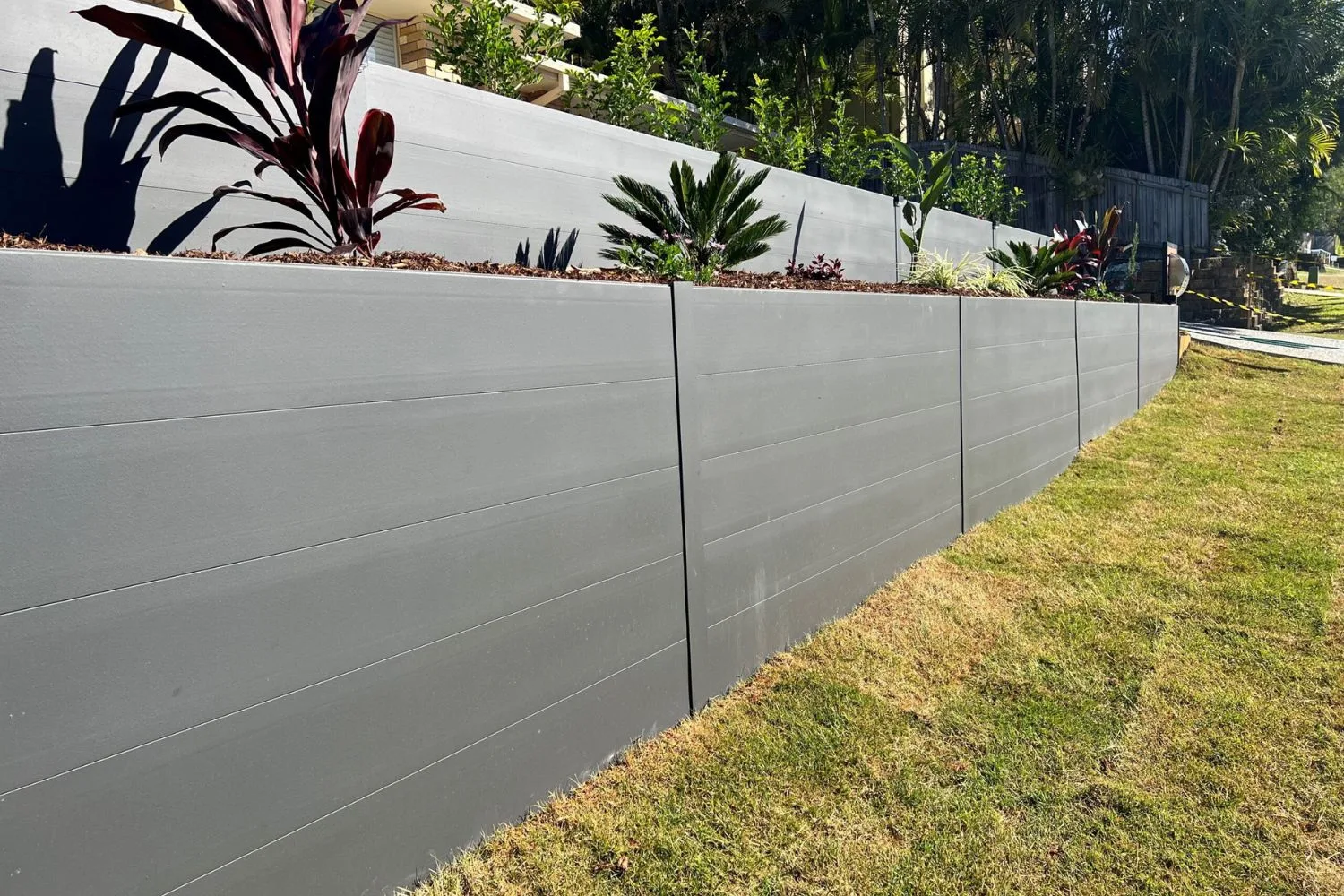 Smooth grey concrete retaining wall beside a lawn