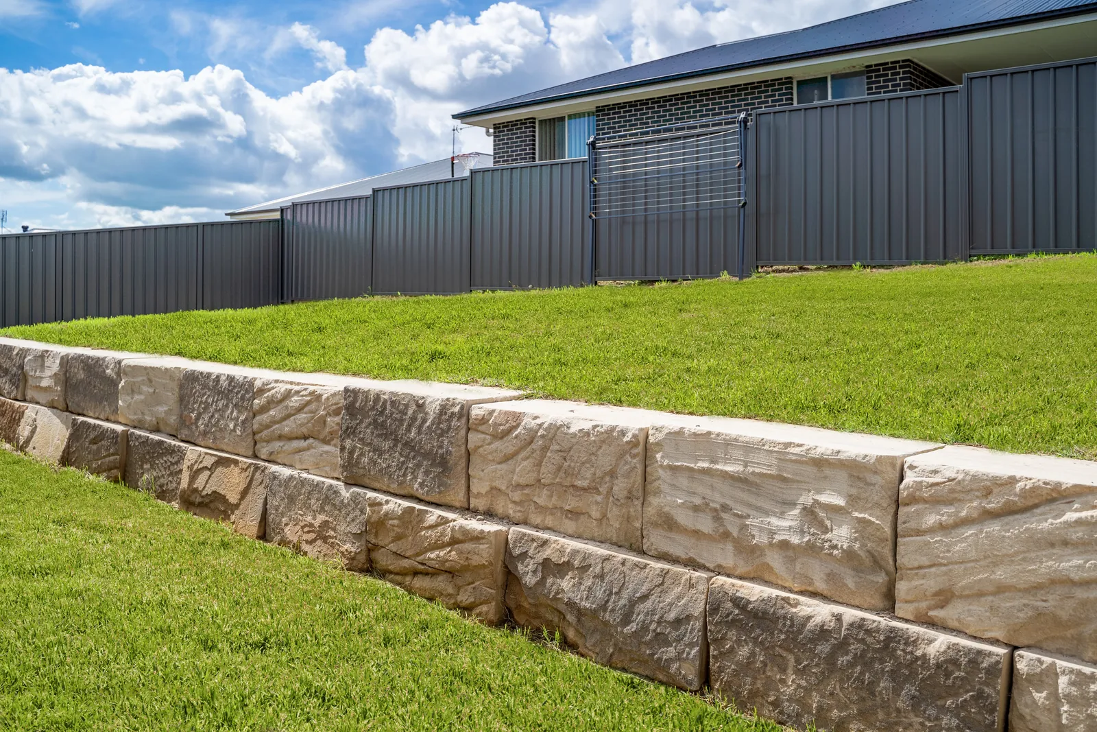 Sandstone block retaining wall supporting a raised lawn