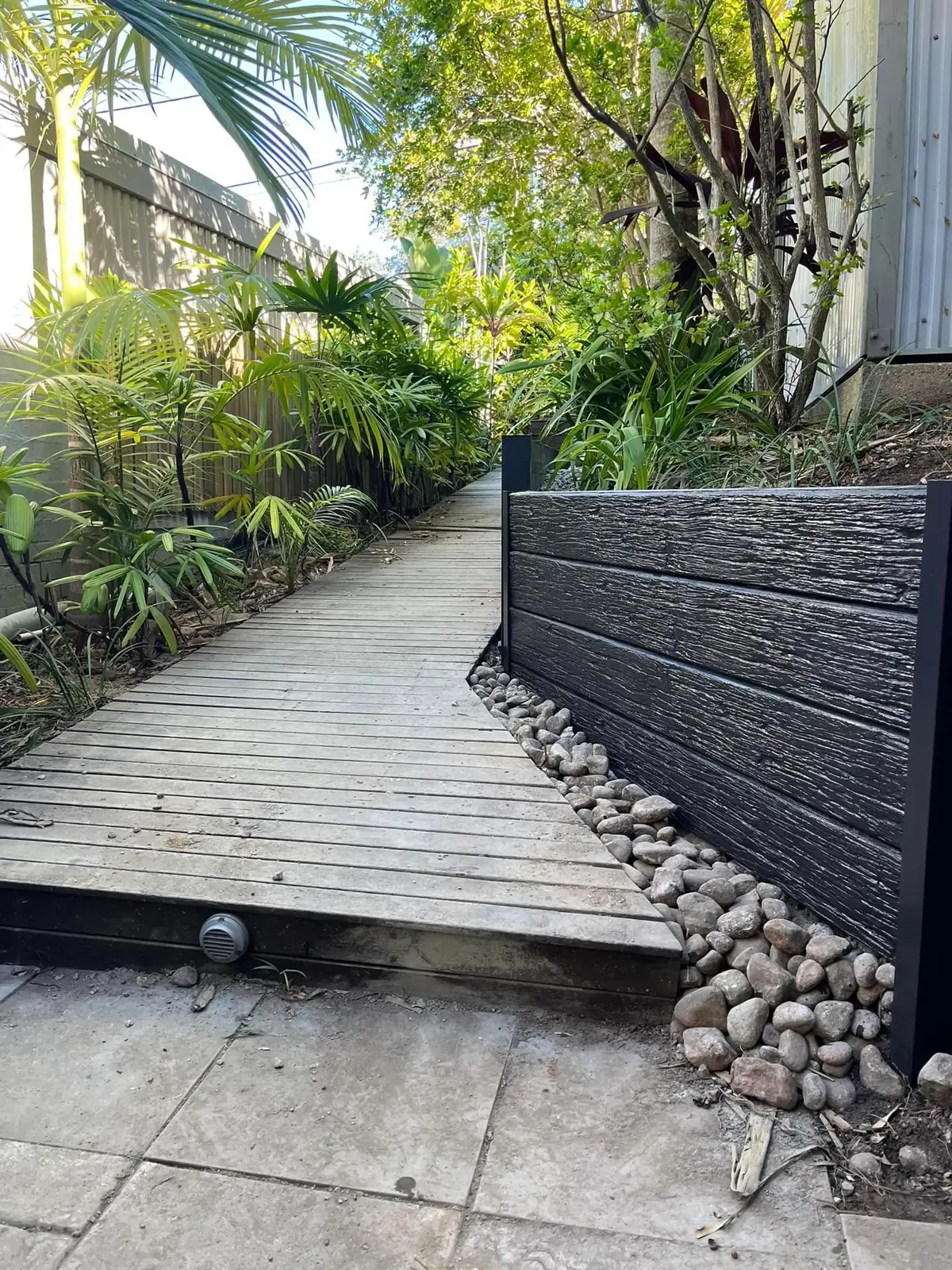 Timber-look concrete retaining wall beside a garden boardwalk