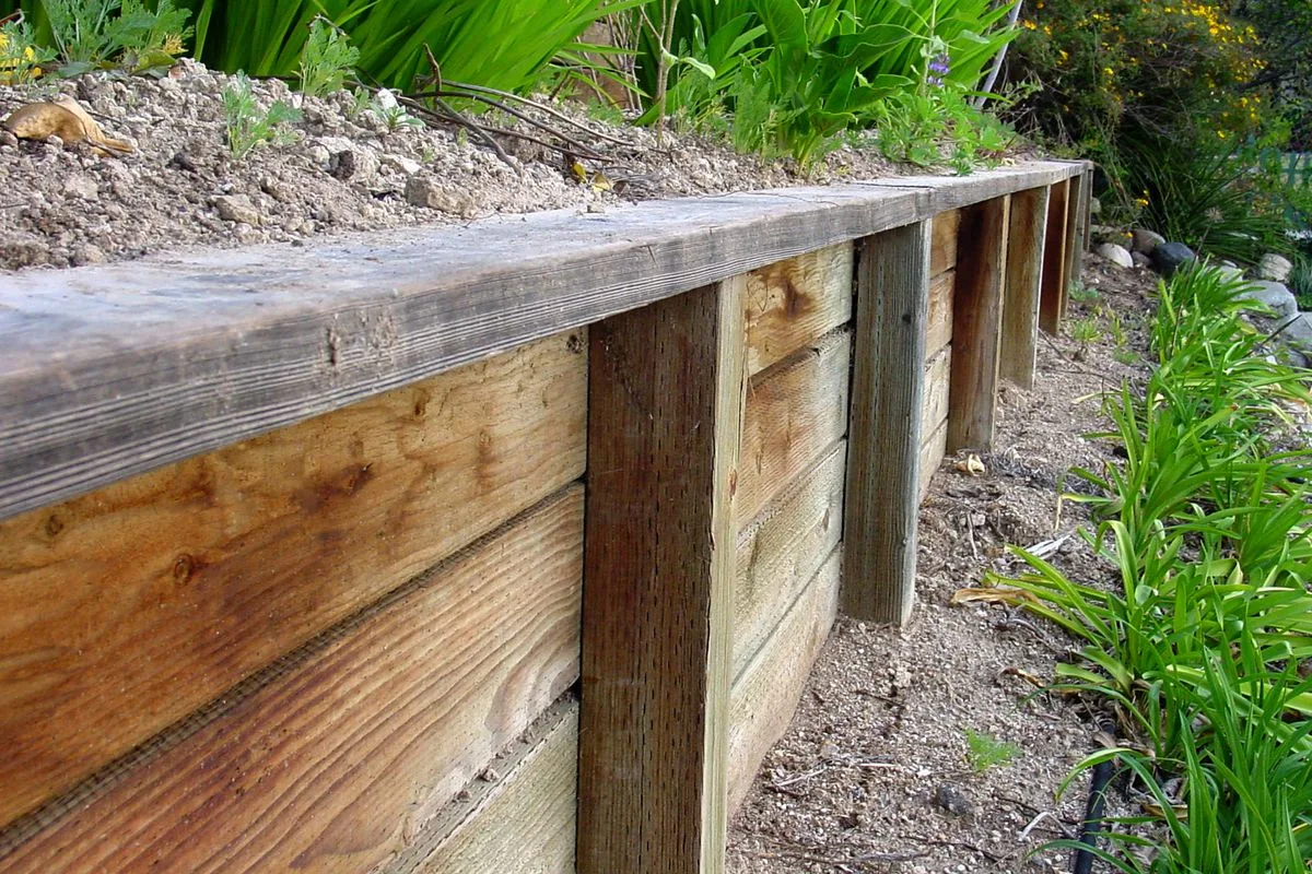 Weathered timber sleeper retaining wall with steel posts
